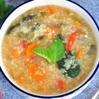Quinoa Soup in a bowl garnished with basil leaves.