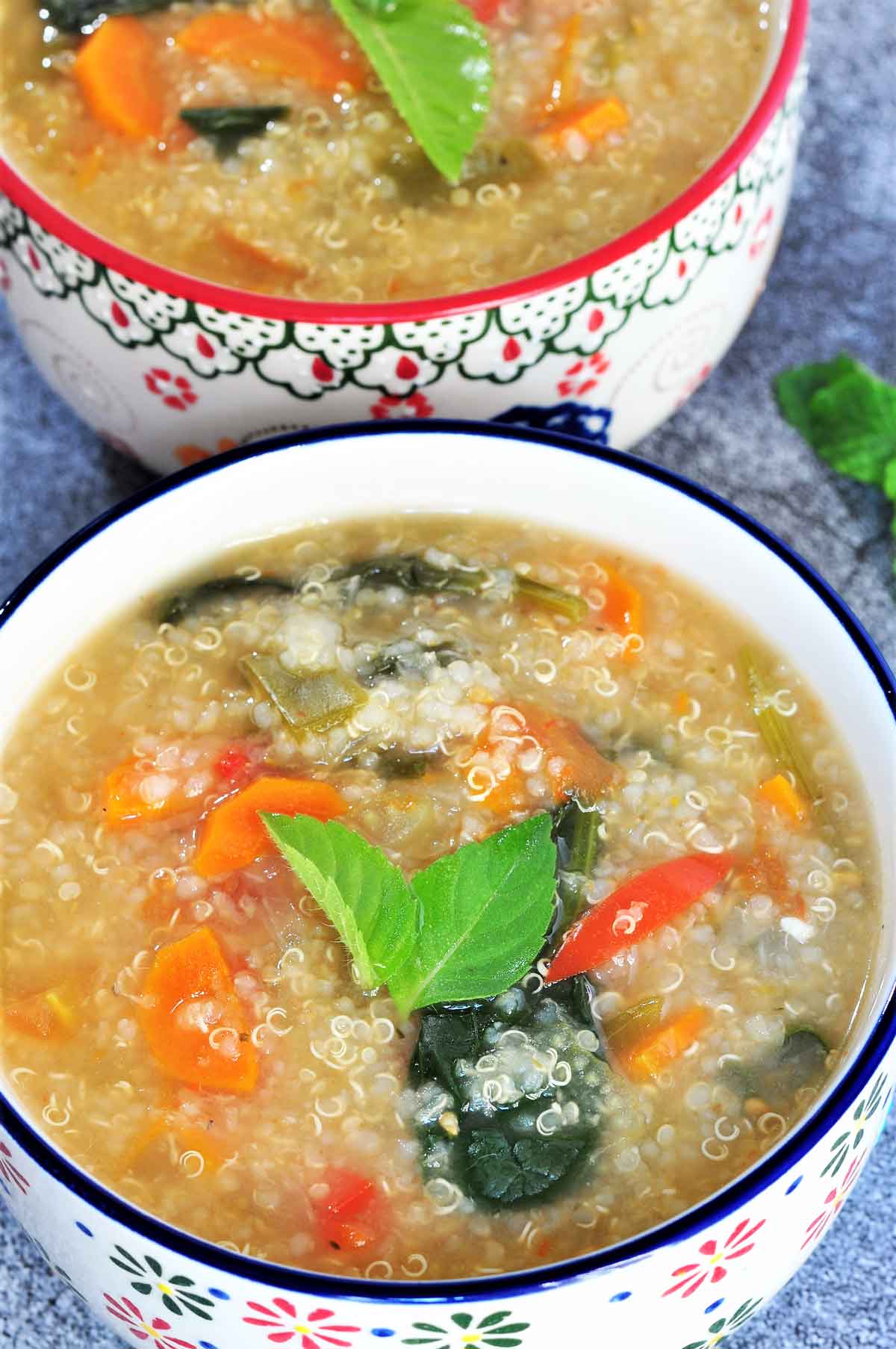 Quinoa Soup in a bowl garnished with basil leaves.