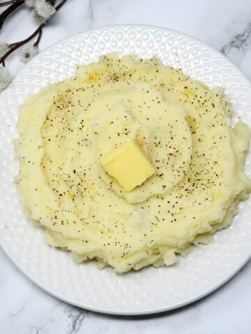 Mashed potato in a plate with butter cube as topping.