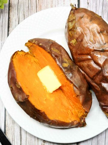 Air fryer whole sweet potatoes topped with butter and served in a plate.