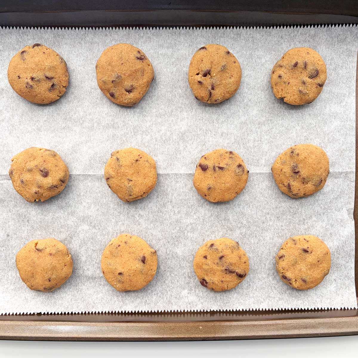 Flattened dough balls for FMF Chocolate Chip cookies in baking tray.