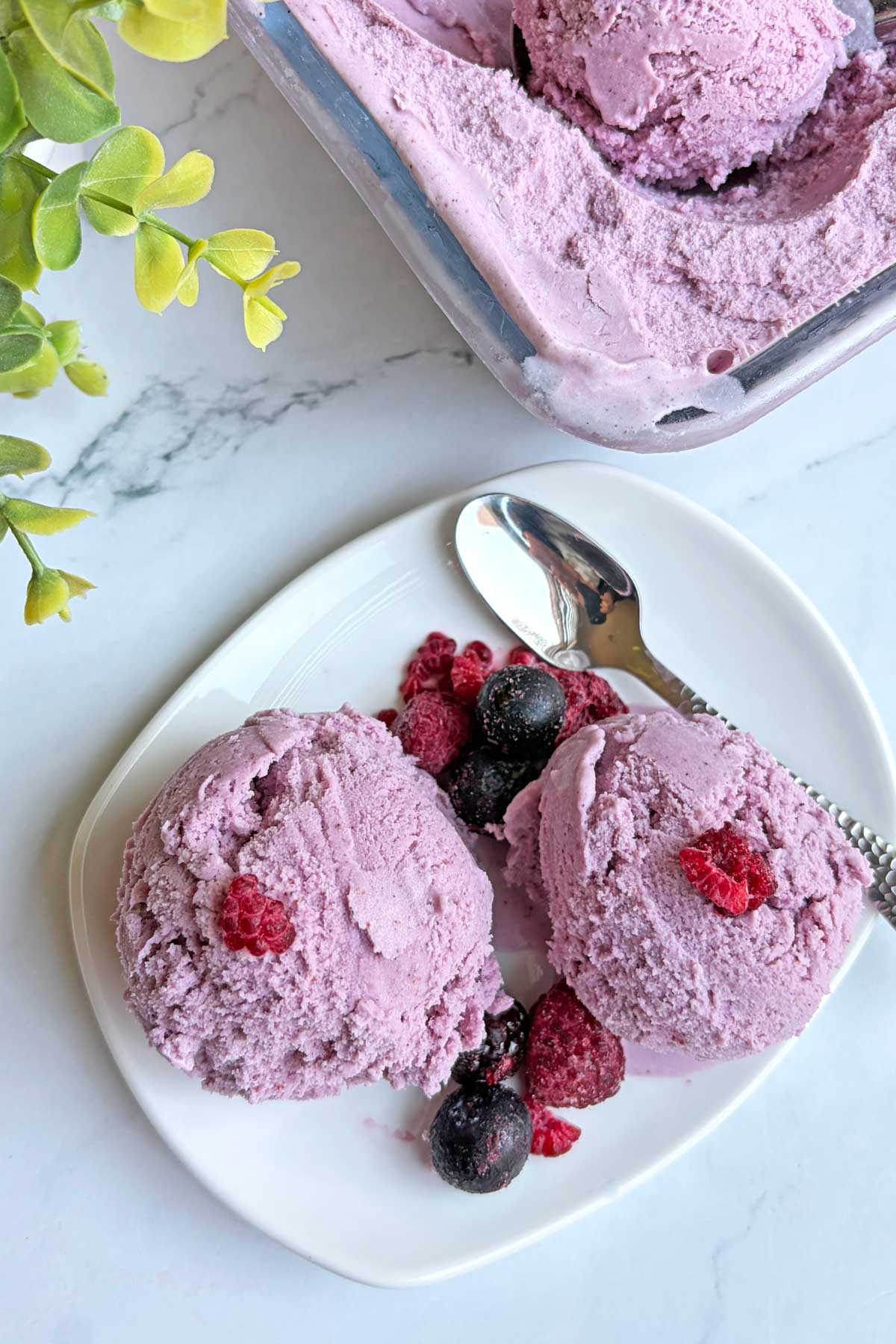 Delicious homemade strawberry ice cream served with fresh berries on a white plate.