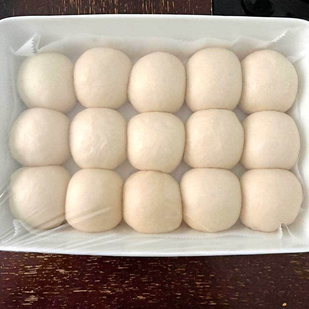 Sourdough dinner rolls balls in a baking tray.